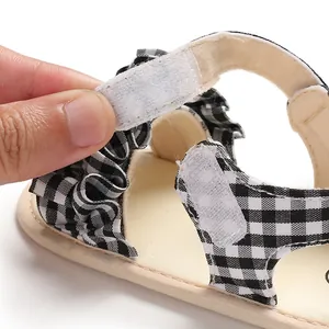Dettaglio del cinturino a strappo sui sandali a quadretti con volant per neonati