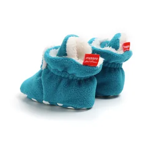 Close-up of soft blue winter baby booties with plush lining and red brand tag.