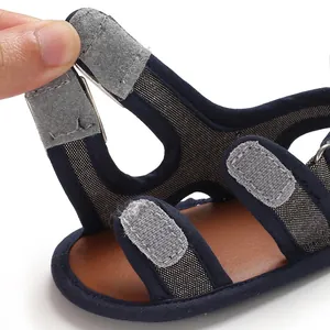 Dettaglio di sandali traspiranti per neonati con cinturini regolabili in velcro grigio.
