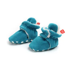 Close-up of cozy cyan fleece baby booties with white plush lining and non-slip sole