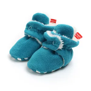 Close-up of soft teal fleece baby booties with plush lining and secure velcro strap.