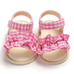 Primo piano dettagliato dei sandali da neonata a quadretti rosa con graziose balze decorative
