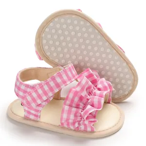 Dettaglio dei sandali per neonati a quadretti rosa con volant e suola morbida antiscivolo.