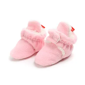 Detailed view of pink fuzzy winter baby booties with soft white fleece lining and snap button