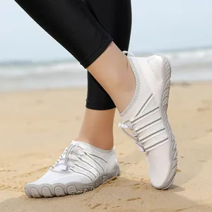 Zapatos de agua blancos de secado rápido para hombre y mujer en fondo de playa arenosa.