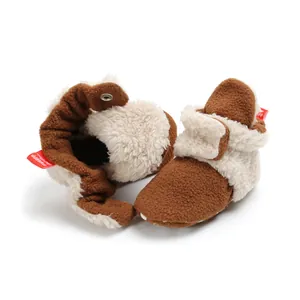 Detailed view of brown plush baby booties with soft white fleece lining and red tag