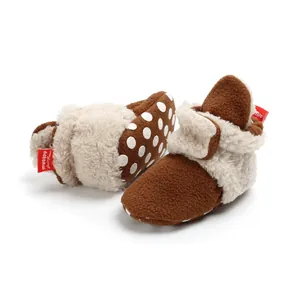 Detail view of plush brown baby winter shoes with cream faux fur and white polka dots