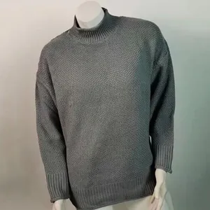 Detalle de suéter gris de cuello alto con textura de punto gofre y puños elásticos