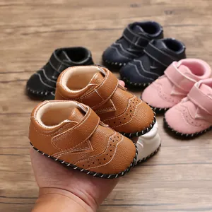 Detail view of brown faux leather baby walking shoes with brogue stitching and velcro strap