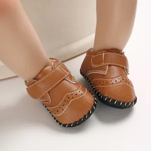 Close-up of brown faux leather baby walking shoes with decorative stitching and brogue detail
