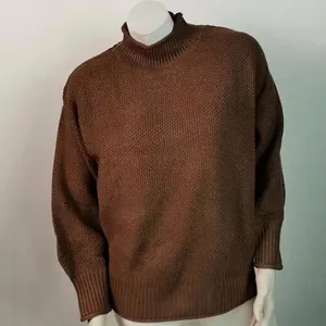 Detalle de un suéter de punto grueso color marrón con cuello alto y acabados en canalé
