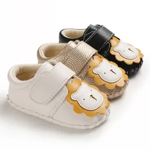 Detailansicht von Baby-Lauflernschuhen in Weiß, Gold und Schwarz mit Löwen-Cartoon-Patch