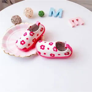 Detailed view of toddler canvas slip-on shoes featuring vibrant red floral patterns.