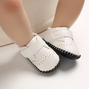 White faux leather baby walking shoes with elegant brogue details and adjustable Velcro strap