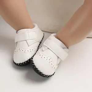 Close-up of white handmade baby walking shoes with stylish perforations and velcro straps