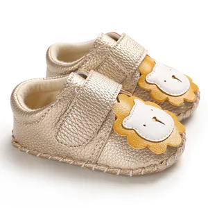 Nahaufnahme goldener Babyschuhe mit einem niedlichem Löwen-Design auf der Vorderseite