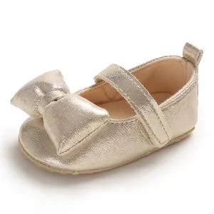 Detailed view of gold metallic baby princess shoe with a large bow and soft sole.
