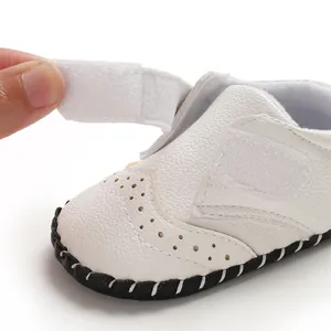 Detail view of the functional hook-and-loop strap on white baby walking shoes