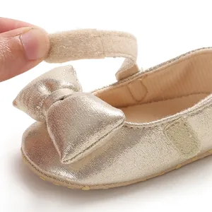 Close-up of baby girl princess shoe with golden bow and hook-and-loop strap detail