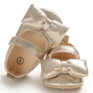 Detailed view of golden baby girl princess shoes featuring a large bow and soft sole