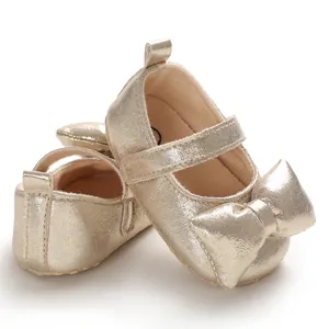 Detailed view of metallic gold baby girl princess shoes featuring a large bow detail
