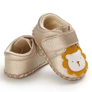 Nahaufnahme von goldenen Lauflernschuhen mit süßem Löwen-Applikationsdesign für Babys.