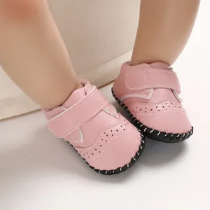 Close-up detail of pink faux leather baby pre-walker shoes featuring brogue perforations