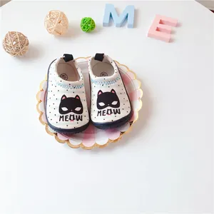 Detail view of white toddler walking shoes with cute black cat pattern and meow print