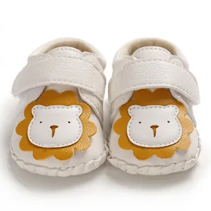 Detailansicht weißer Babyschuhe mit einem niedlichen gelben Löwen-Cartoon-Gesicht.