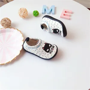 Detailed view of cute cat pattern on white striped toddler canvas slip-on shoes.