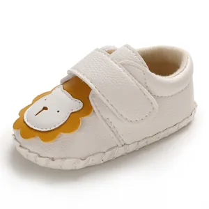 Nahaufnahme eines Babyschuhs mit süßem Löwenmotiv und strukturiertem weißem Leder