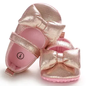 Close-up detail of shiny pink metallic baby princess shoes with a large decorative bow