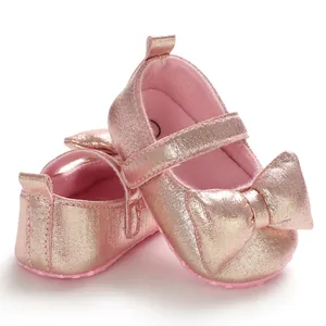 Detail of shiny rose gold baby princess shoes with metallic finish and bow decor