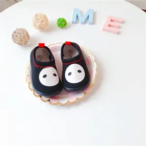 Detailed view of black minimalist pig face slip-on shoes for toddlers on a decorative plate