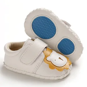 Nahaufnahme weißer Lauflernschuhe mit Löwen-Cartoon und blauer rutschfester Gummisohle.