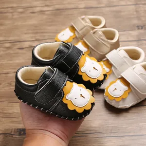 Detailansicht schwarzer Baby-Lauflernschuhe mit Löwen-Design und Klettverschluss.