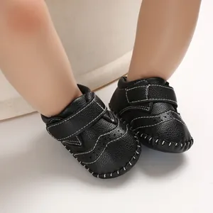 Close-up of stylish black handmade leather baby shoes with contrast white stitching details
