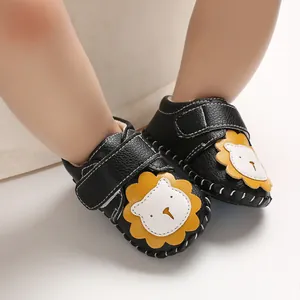 Detaillierte Nahaufnahme schwarzer Baby-Lernlaufschuhe mit gelbem Löwen-Motiv.