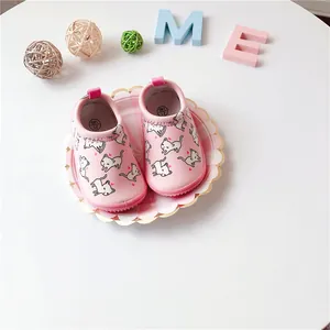 Detailed top view of pink baby walking shoes with cute cat patterns on a plate.