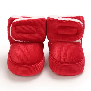 Gros plan sur des bottes en velours côtelé rouge pour bébé avec doublure en polaire blanche.