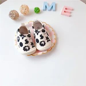 Detail of baby slip-on canvas shoes with black cartoon animal patterns on white