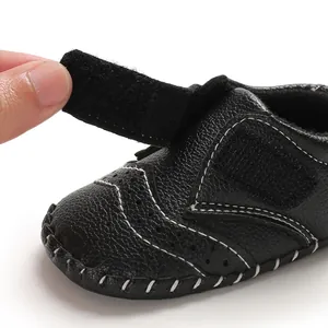Detail of black baby walking shoe featuring a Velcro strap and white stitching.
