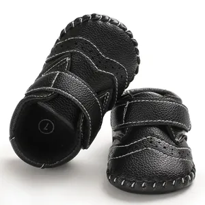 Close-up detail of black handmade leather baby walker shoes with white stitching and soft soles.