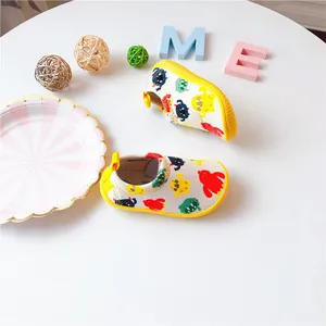 Detail of toddler slip-on shoes featuring colorful monster patterns and yellow soles.