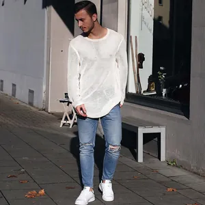 Mann in weißem Mesh-Strickpullover draußen auf einem Gehweg