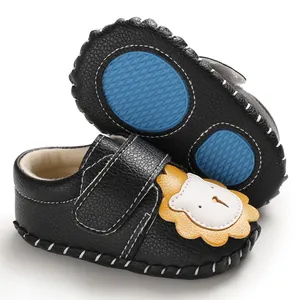 Detail schwarzer Lauflernschuhe mit blauer Gummisohle und Cartoon-Löwen-Design.