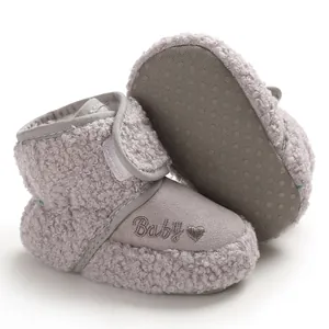 Detailed macro shot of grey fuzzy baby snow boots with Baby embroidery and soft sole
