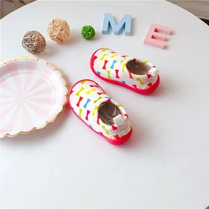 Detail of toddler canvas slip-on shoes with colorful bow print and red rubber sole