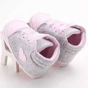 Detailansicht von rosa gepunkteten Babyschuhen mit Herzaufnäher und Bändern