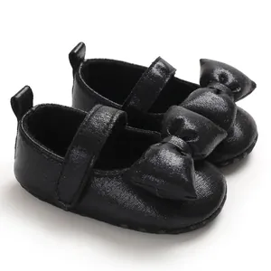 Close-up of black baby girl princess shoes with a large decorative bow.